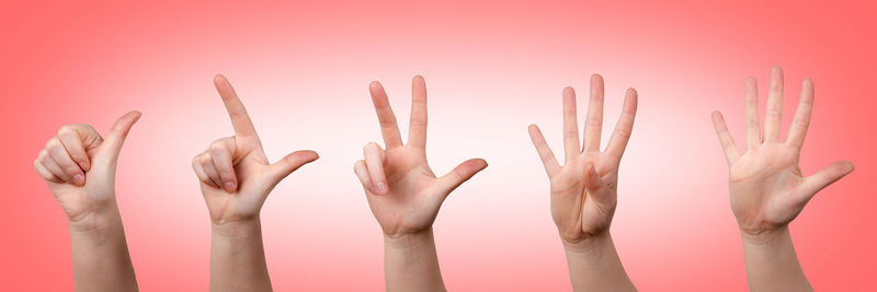 Close-up of hands gesturing against colored background