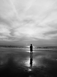Silhouette man standing at beach against sky