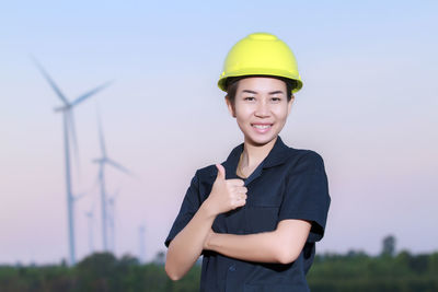 Portrait of engineer holding blueprint against sky