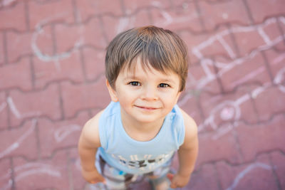 High angle view portrait of smiling boy standing on footpath