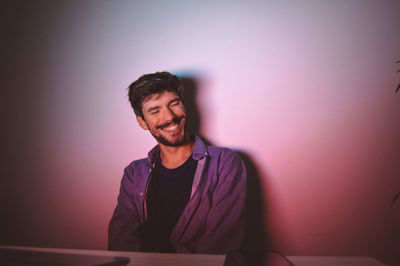 Portrait of a smiling young man sitting against wall