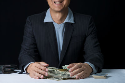 Midsection of man holding paper against black background