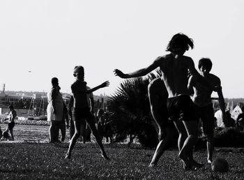Group of people playing soccer on land against sky