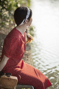 Woman sitting on pier by lake