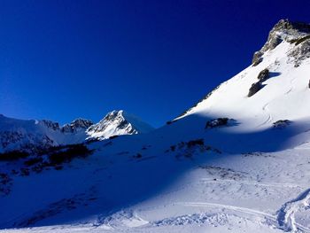 Scenic view of snowcapped mountains against clear blue sky