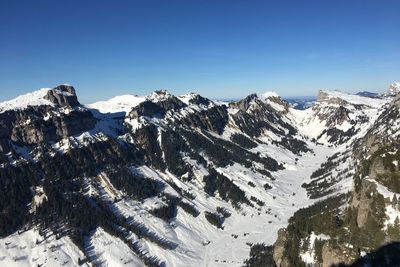 Scenic view of snowcapped mountains against blue sky