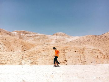 Woman walking against mountains at desert during sunny day