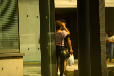 Side view of woman standing by window