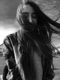 Woman with long hair standing on field against sky