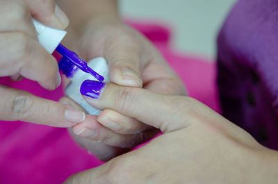 Cropped hand applying nail polish to woman