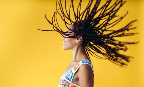 Rear view of woman standing against yellow background