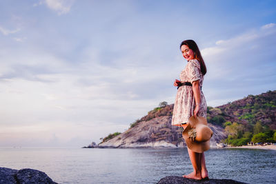 Woman standing by sea against sky