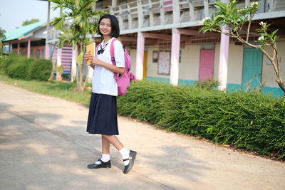 Portrait of teenage girl in school uniform standing on road