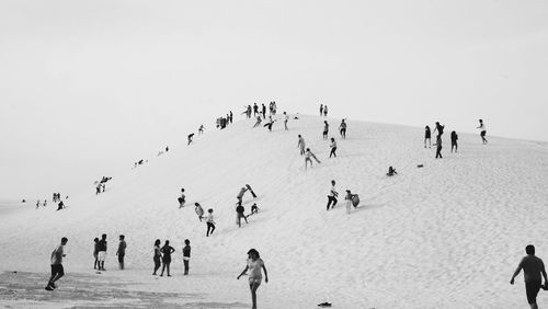 Group of people on sand dune against sky