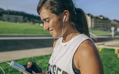 Side view of woman using phone at park