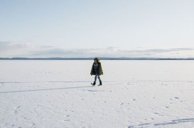 Boy walking across a frozen lake alone in sweden