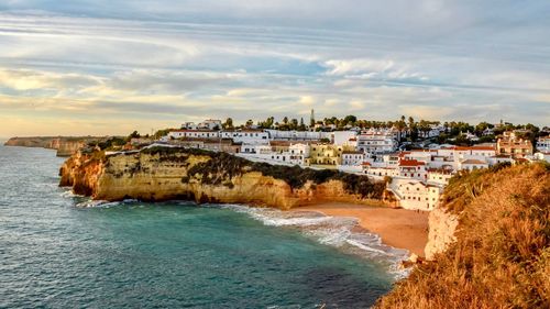 Scenic view of beach by city against sky