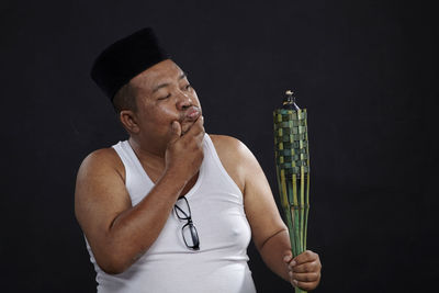 Close-up of man wearing hat against black background