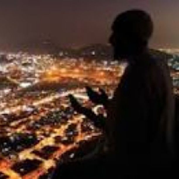 night, lifestyles, rear view, leisure activity, illuminated, selective focus, standing, focus on foreground, men, outdoors, built structure, person, rock - object, casual clothing, architecture, sitting, high angle view