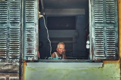 Portrait of man looking through window