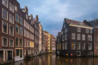 Buildings by canal against sky