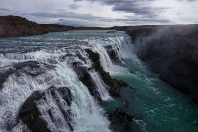 Scenic view of waterfall against sky