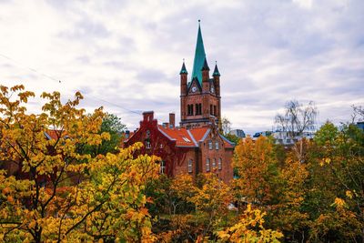 Low angle view of trees and building against sky