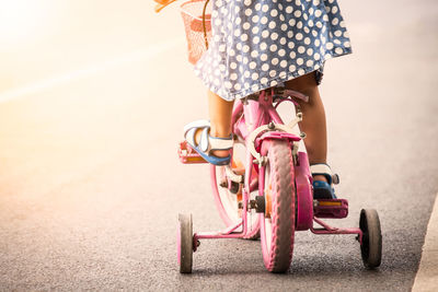 Low section of girl cycling on road