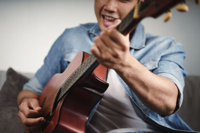 Midsection of man playing guitar