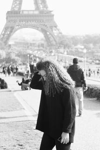 Beautiful young woman standing against eiffel tower