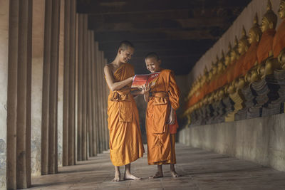 Monks smiling while reading book in corridor