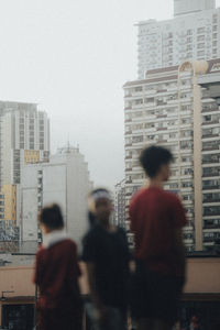 Rear view of people standing against buildings in city