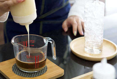 Midsection of person pouring drink in glass