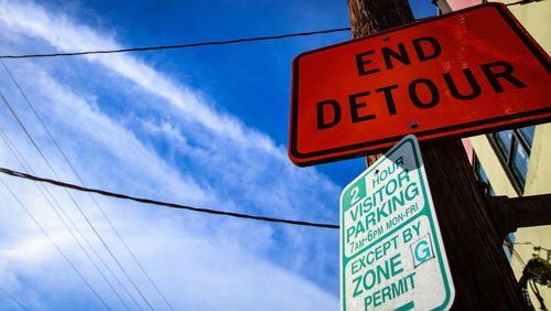 Low angle view of road sign against blue sky