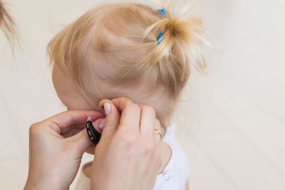 Close-up of mother adjusting hearing aid of daughter
