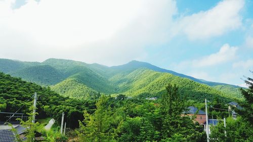 Scenic view of green mountains against cloudy sky