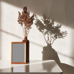  wooden brown frame mock up, clay vase with brown dried flowers on a white coffee table 