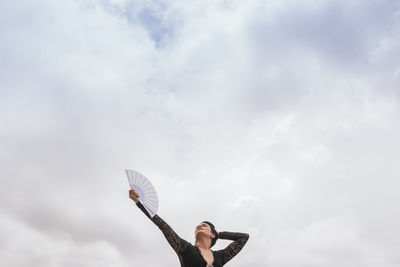 Low angle view of woman with arms raised against sky