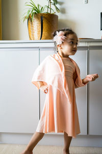 A little girl is standing in a beautiful dress with hair accessories. pretend play at home.