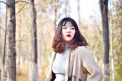 Beautiful young woman looking away while standing at forest