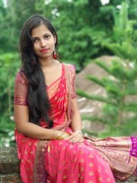 Portrait of beautiful young woman sitting outdoors