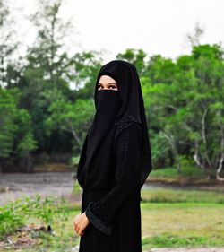 Woman standing on cross against trees