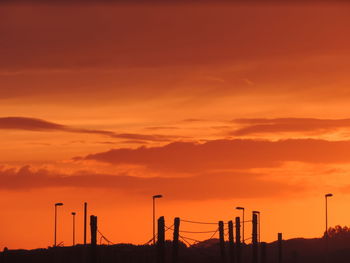 Silhouette of factory against sky during sunset