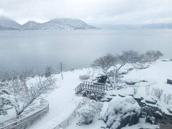 Scenic view of lake by snow covered mountains against sky