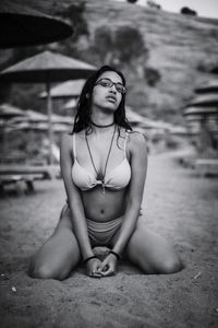 Portrait of young woman wearing bikini sitting at beach
