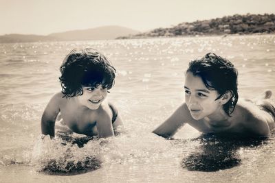 Shirtless siblings enjoying in sea
