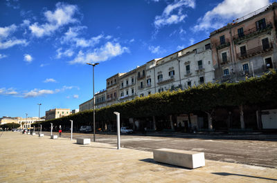 Street by buildings in town against sky