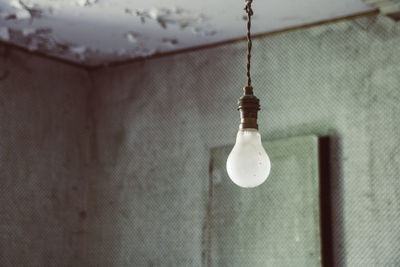 Close-up of light bulb hanging on wall