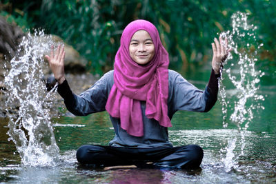 Portrait of smiling teenage girl splashing water in river