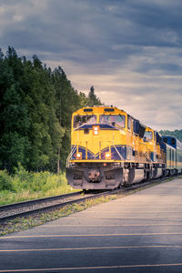 Train arriving at railroad station platform against sky